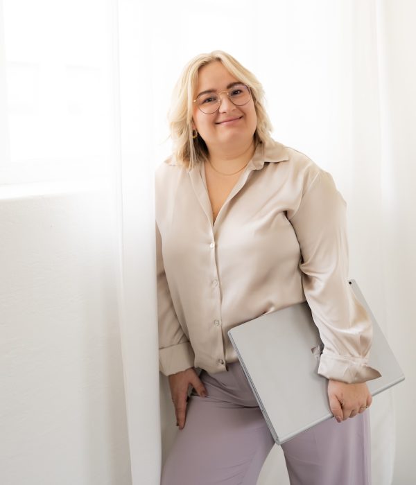 Katharina Heimberger mit Laptop am Fenster. Hält einen Laptop in der Hand. Finanzberatung mit Herz und Verstand in Landshut und Umgebung